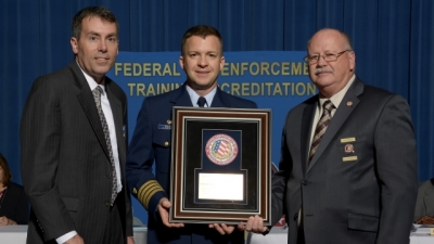 FLETA Board Chair Brian Peters (left) and FLETA Executive Director Gary Mitchell, Ph.D. present USCG Captain Thomas Walsh with the FLETA Agency Leadership Recognition Award